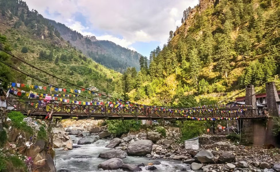 Suspension bridge over mountain river in Himalayas, adorned with prayer flags.